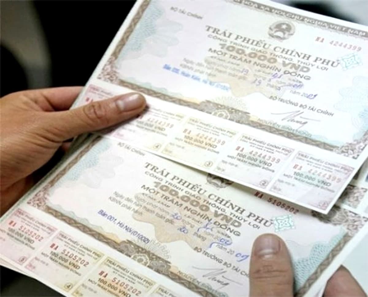 Government bond certificates held in hand, showing denomination and coupon detail