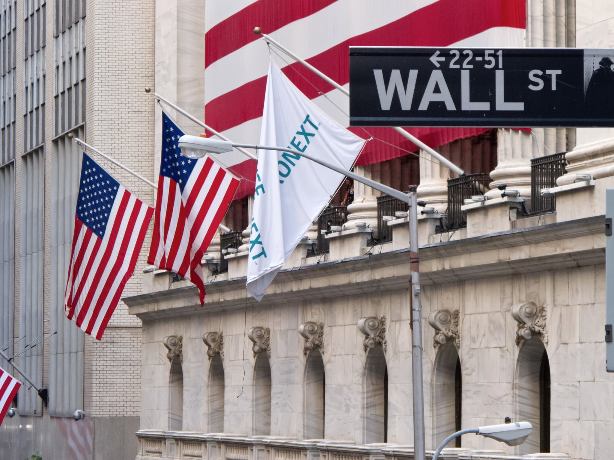 The Wall Street sign and flags on the New York Stock Exchange facade